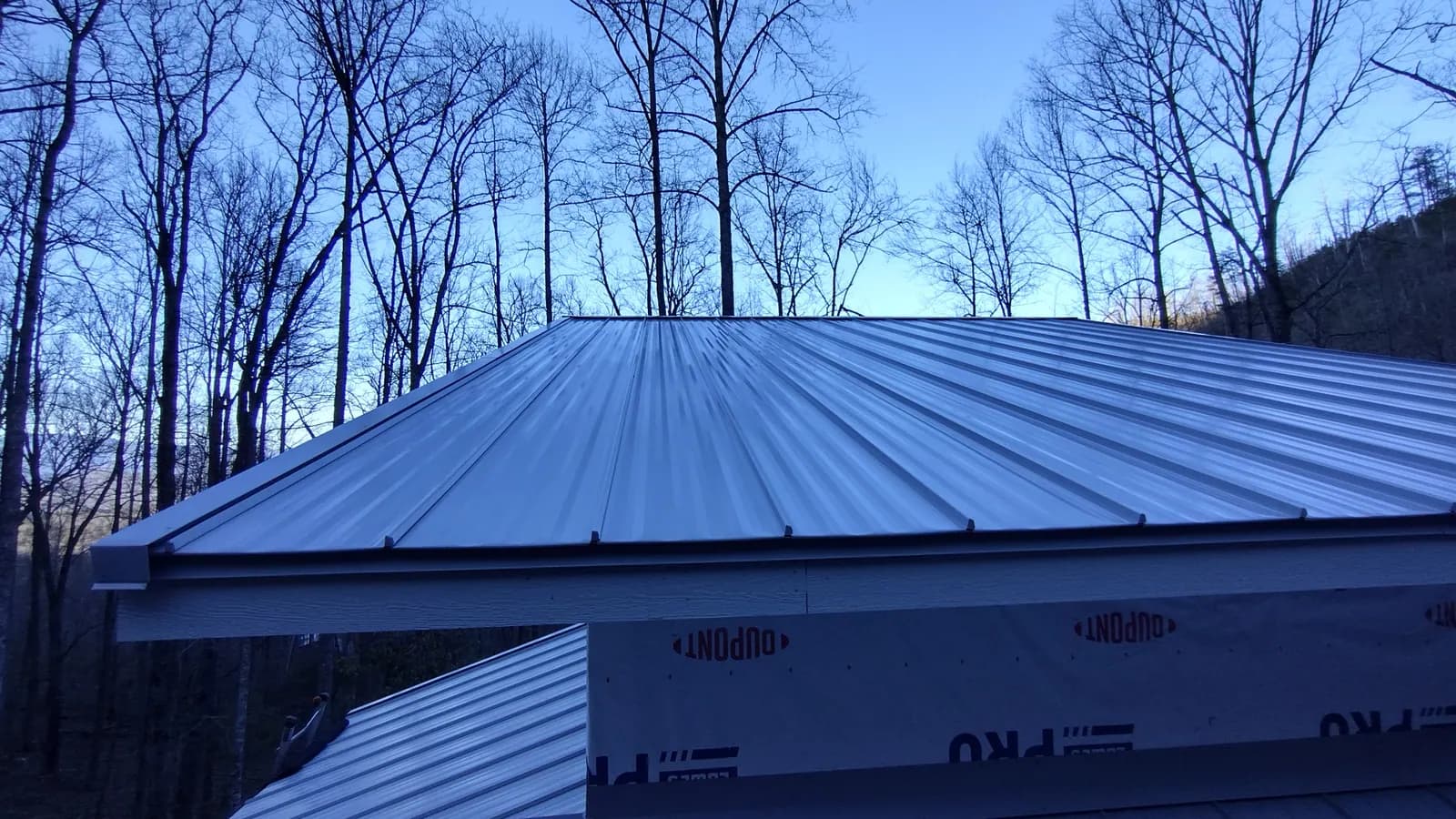 New standing seam metal roof on a house in winter woods