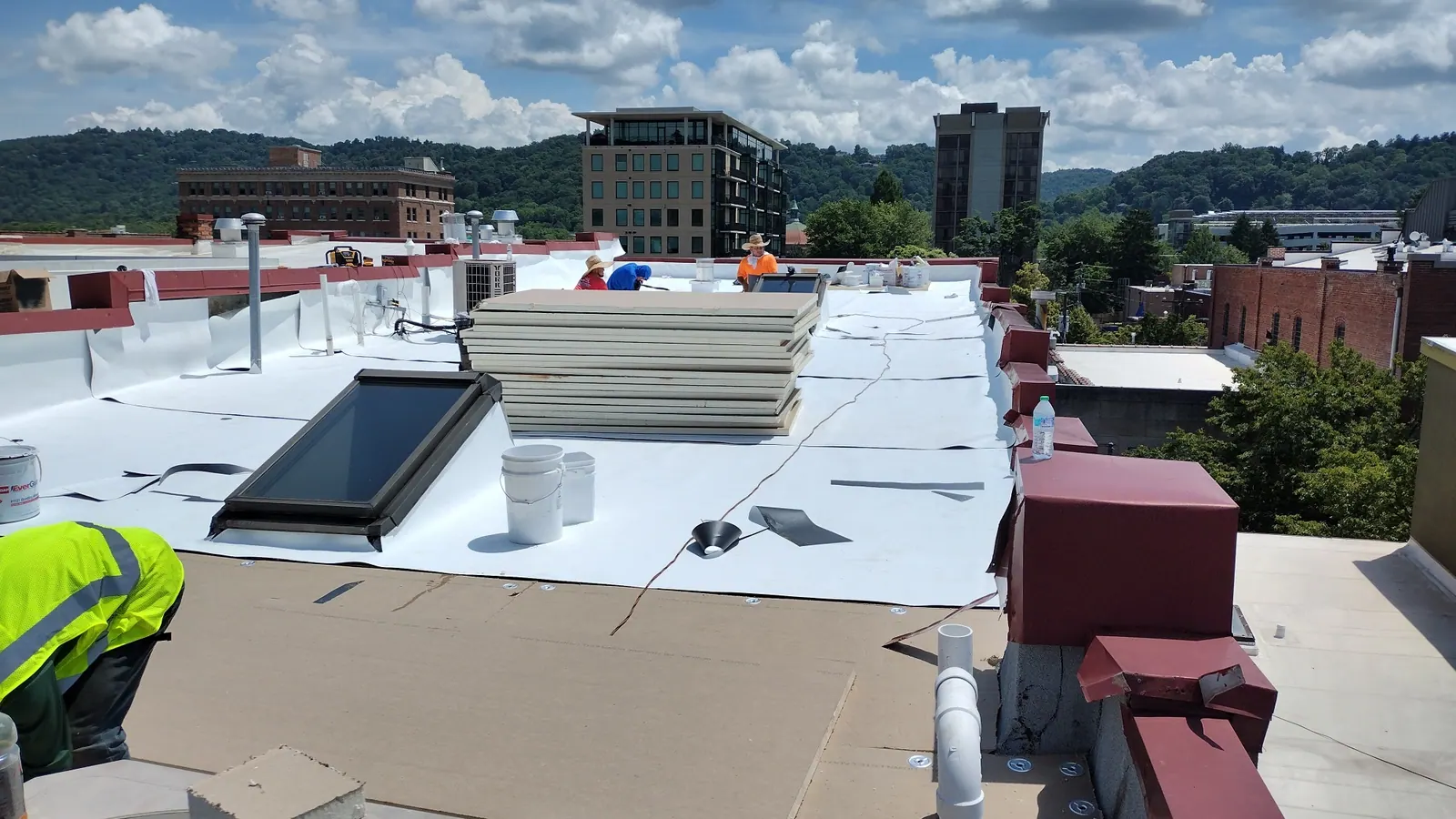 Commercial low-slope roof with a white membrane being installed
